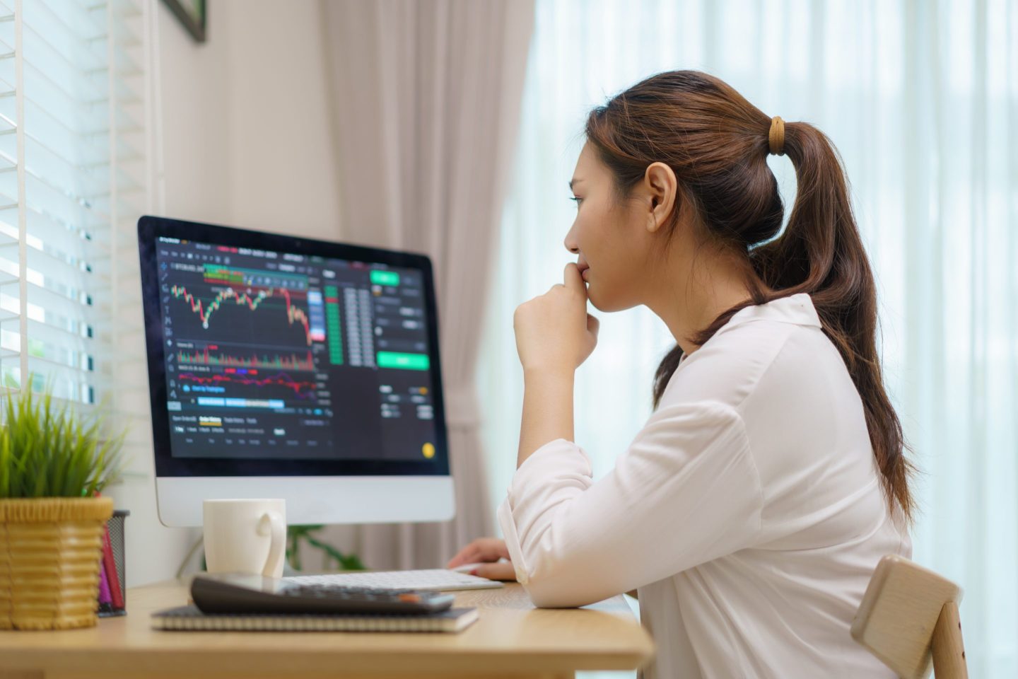 Woman sitting at desk trading stocks.