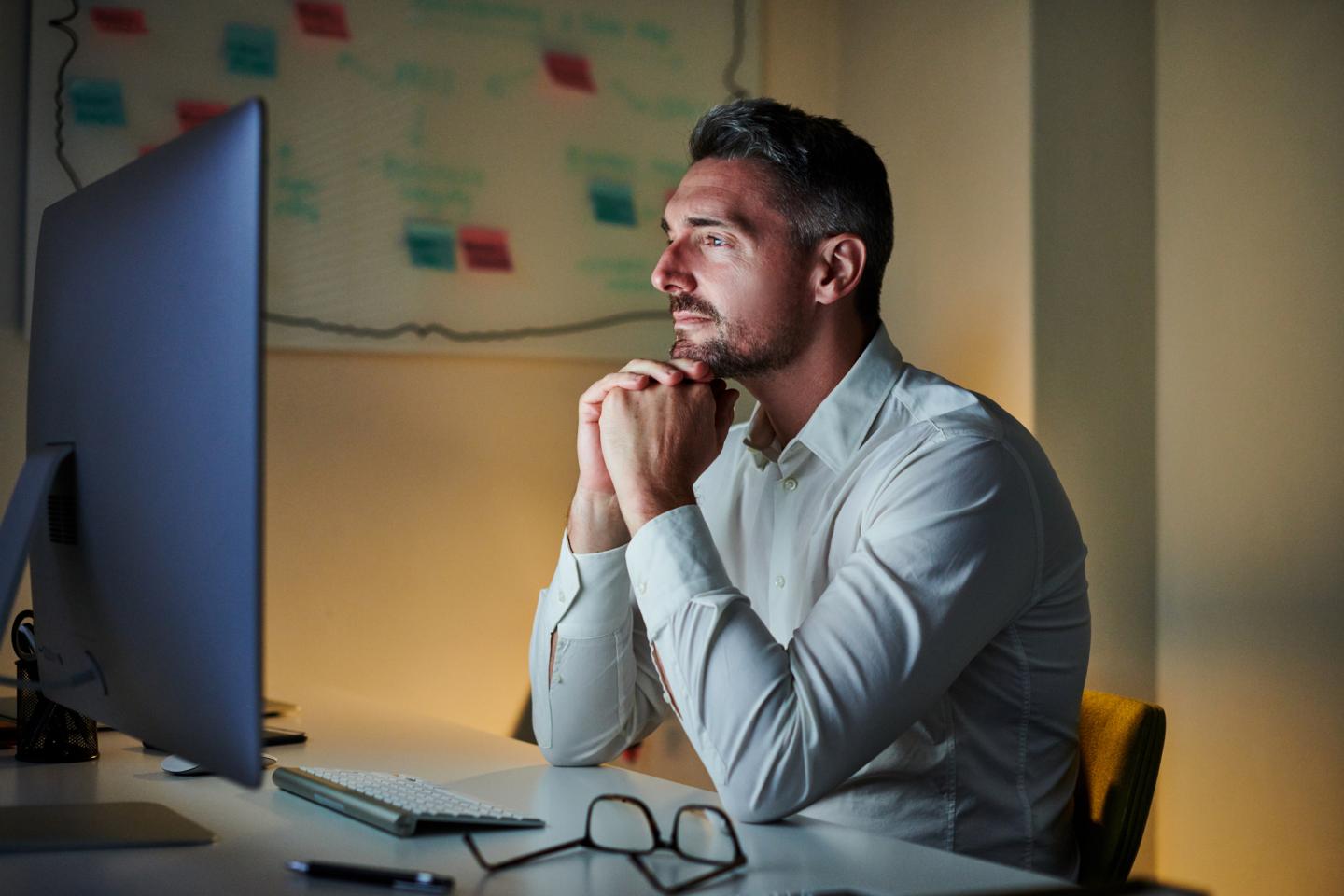 A businessman sits in an office working on a computer.