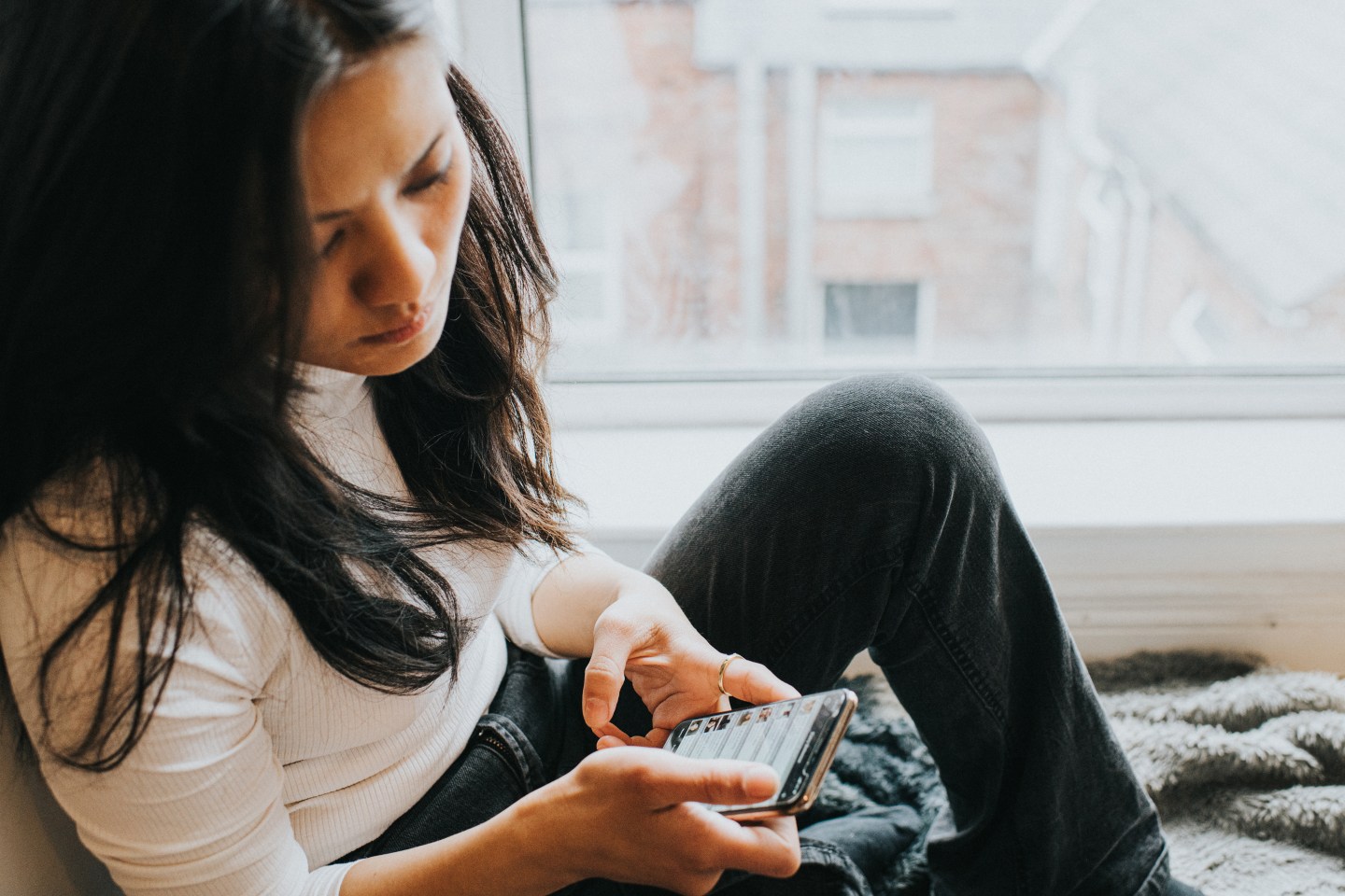 An elevated view of a concerned looking woman looking down at her mobile phone device.