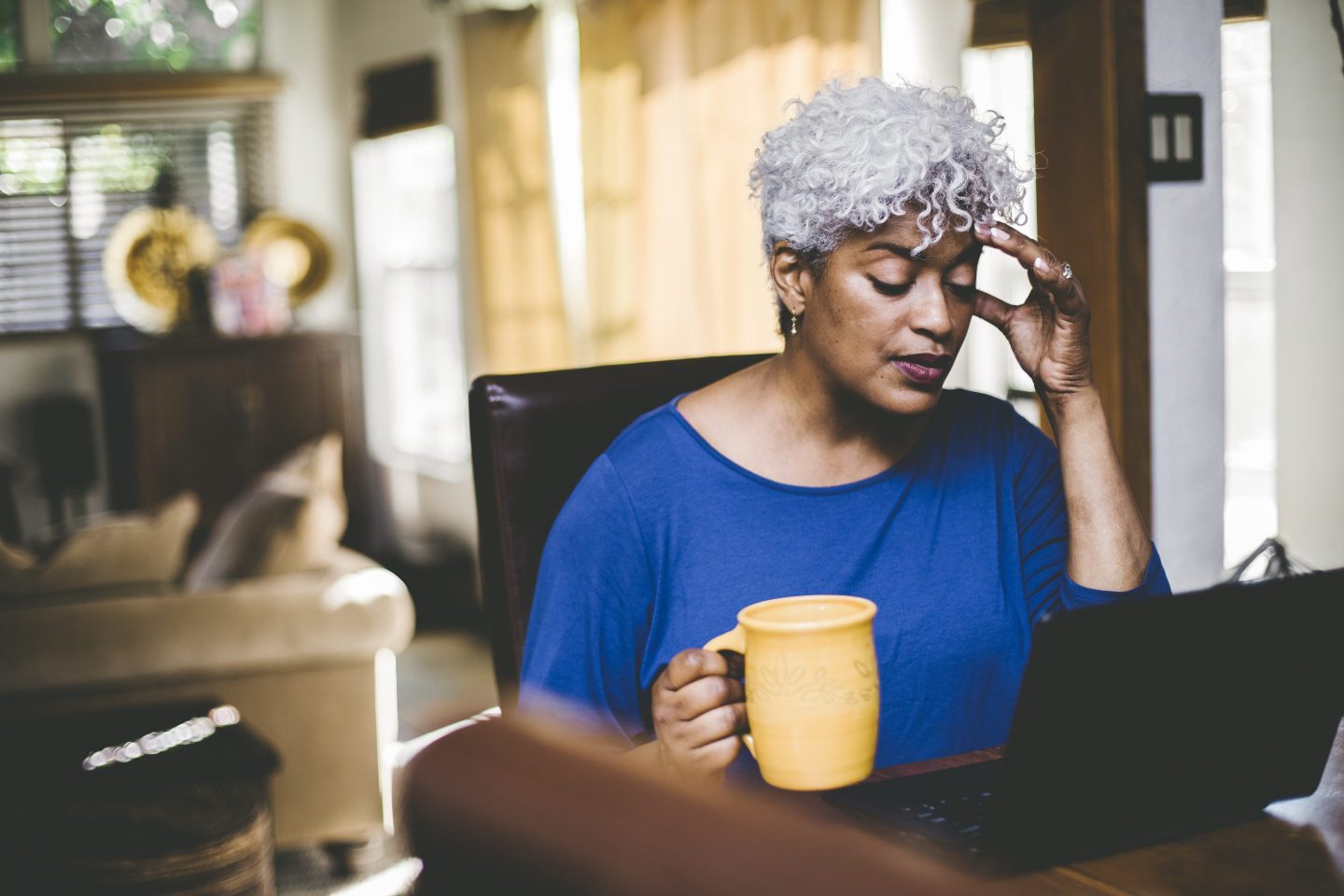 Stressed out woman working at laptop on table at home