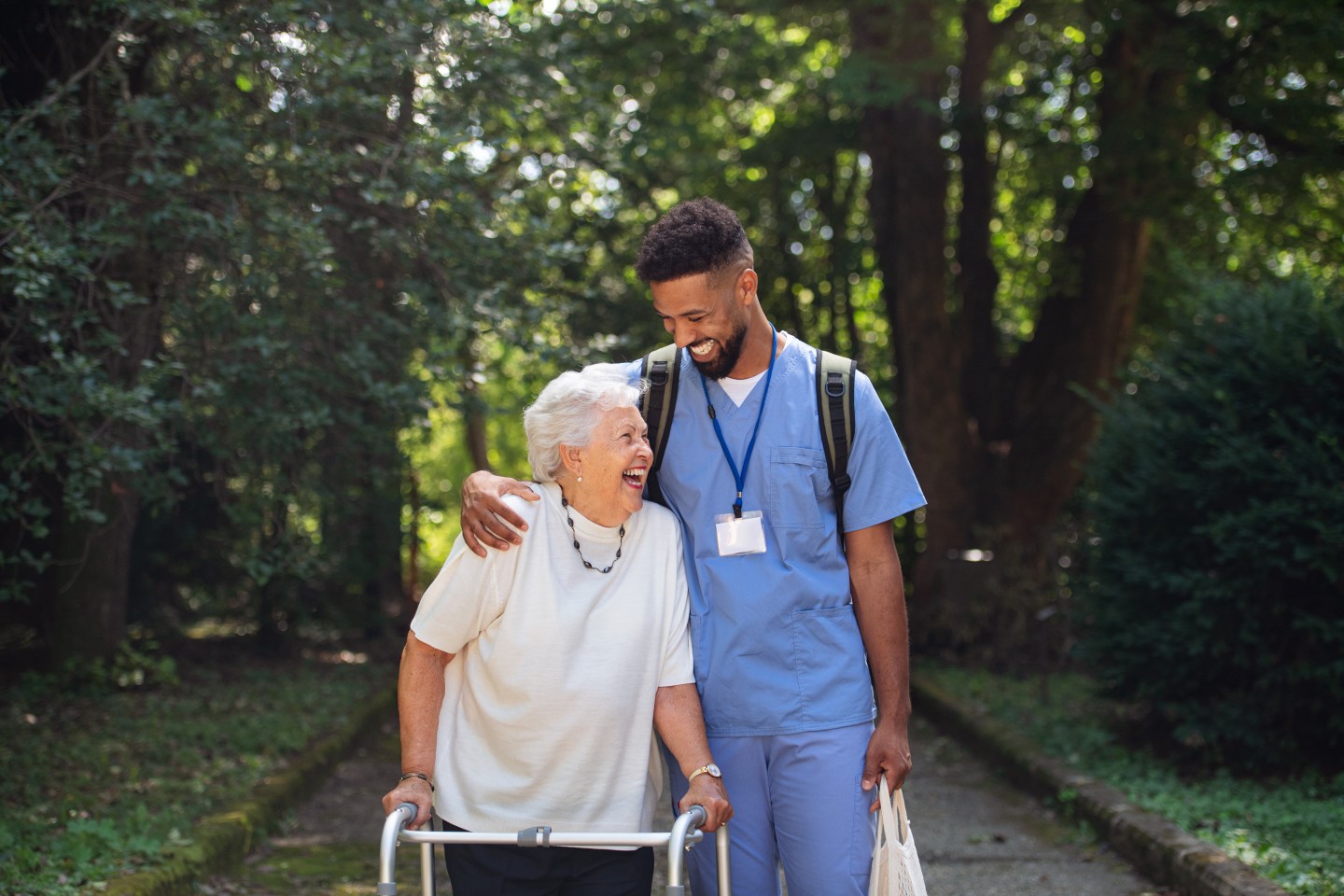 A caregiver walking with an elderly woman.
