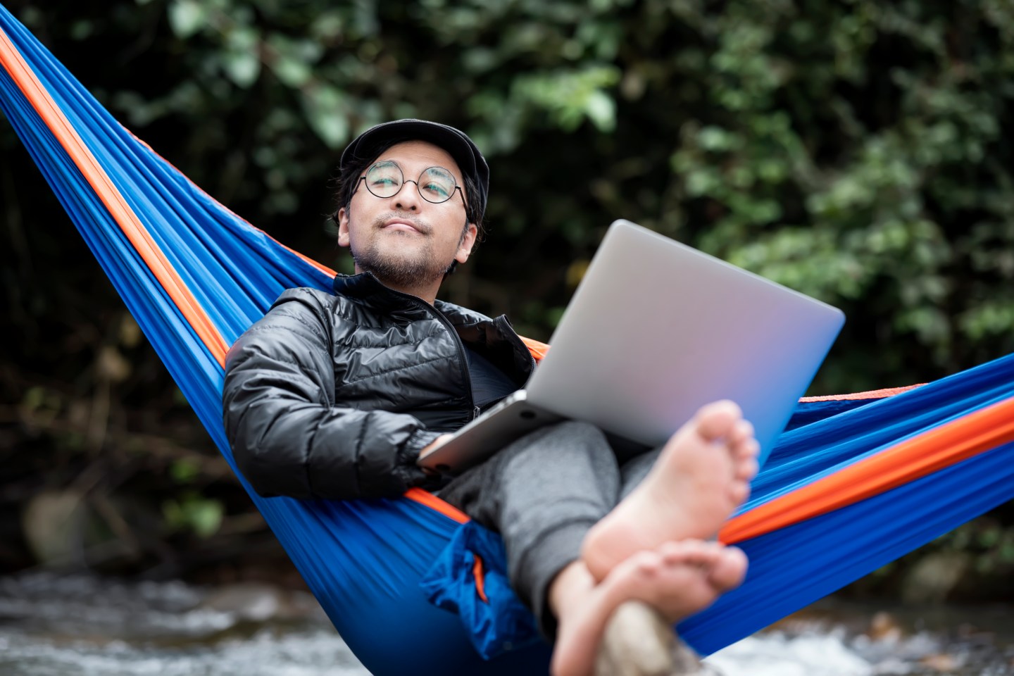 Man relaxing in hammock with laptop