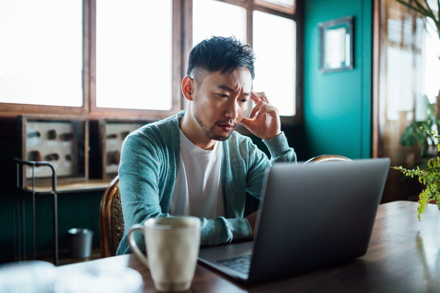 Young man with hand on head looking at computer