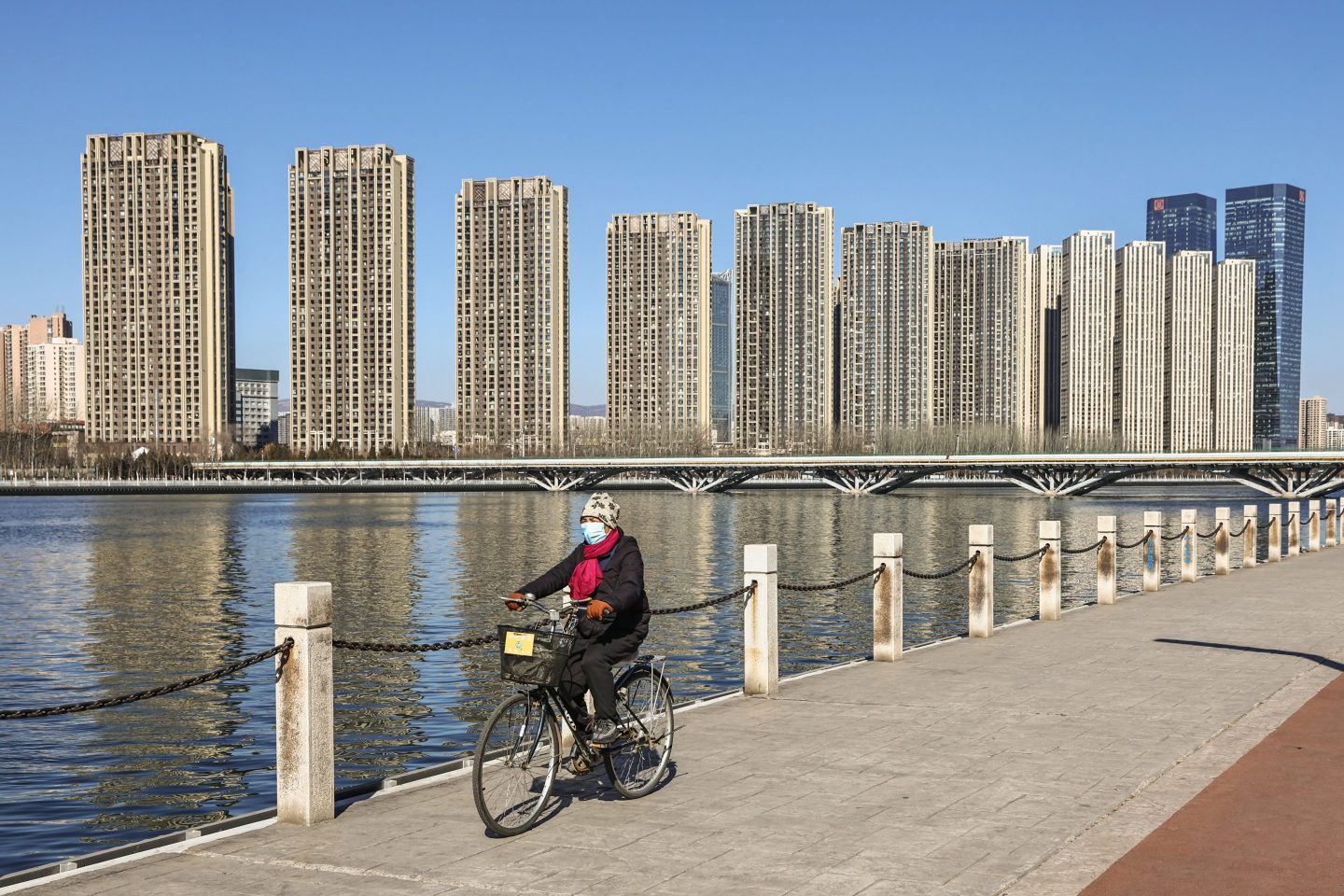 A cyclist rides past residential buildings on the banks of a river on March 1, 2022 in Taiyuan, Shanxi Province of China.
