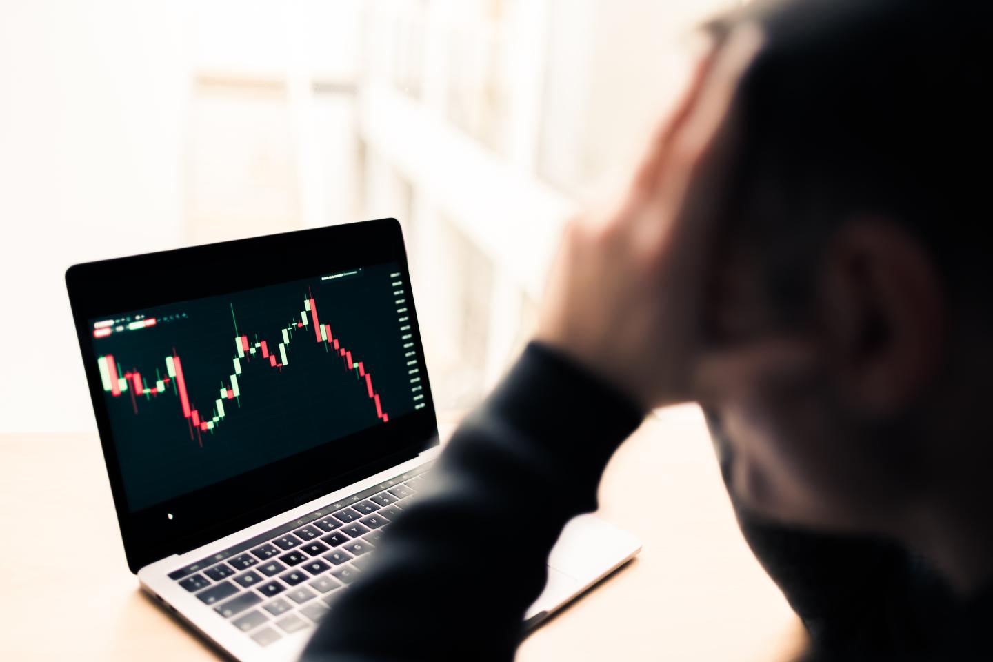 Pensive and sad man watching in his office the crash of the graph through the laptop