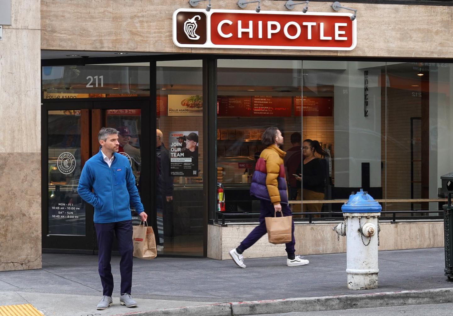 Pedestrians walking in front of a Chipotle store in San Francisco, California