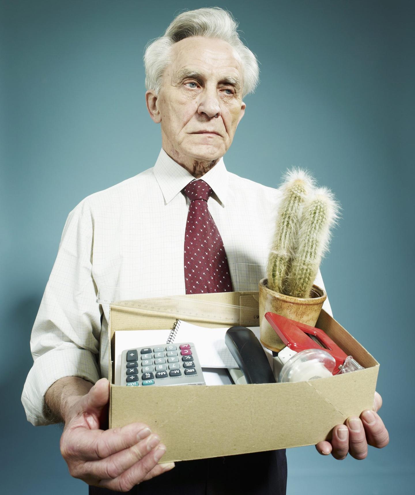 A senior man carrying a box of possessions after being fired