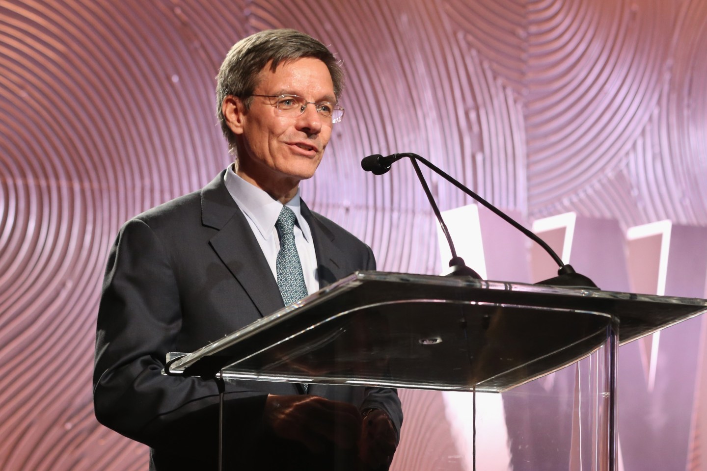 Allstate CEO Tom Wilson speaking at a podium.