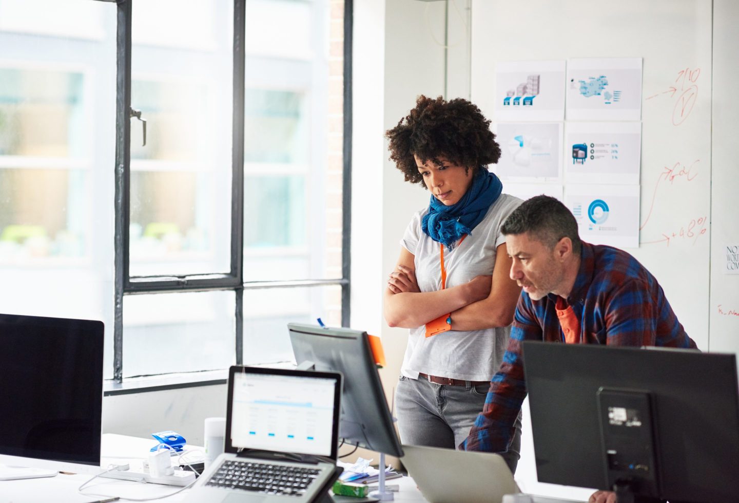 A businessman and businesswoman working together on a computer in a tech start-up office