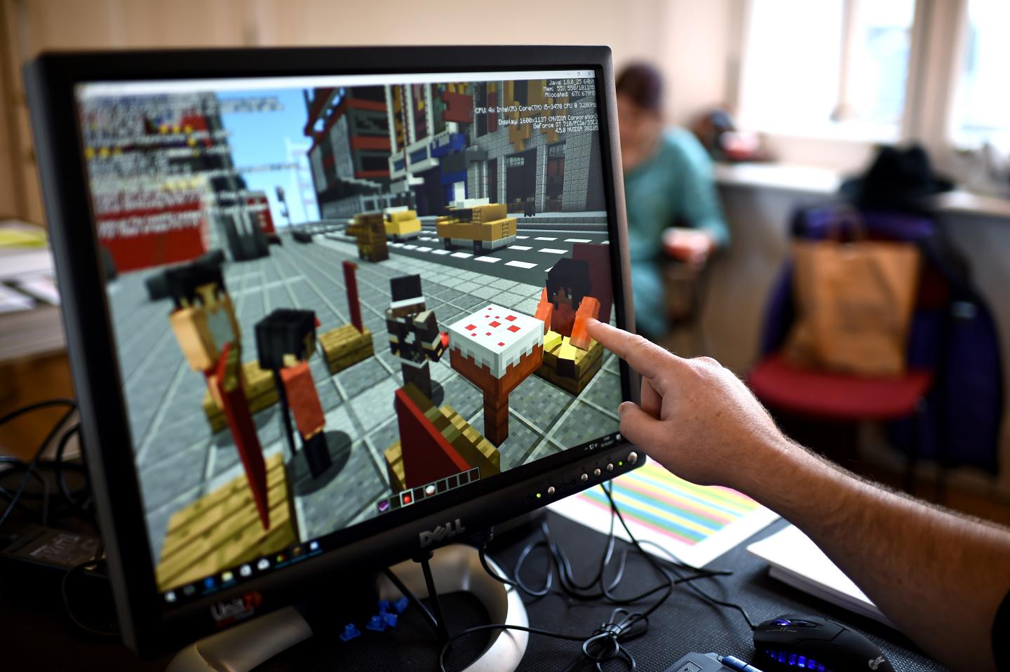 A Minecraft digital artist points at a virtual version of his character
