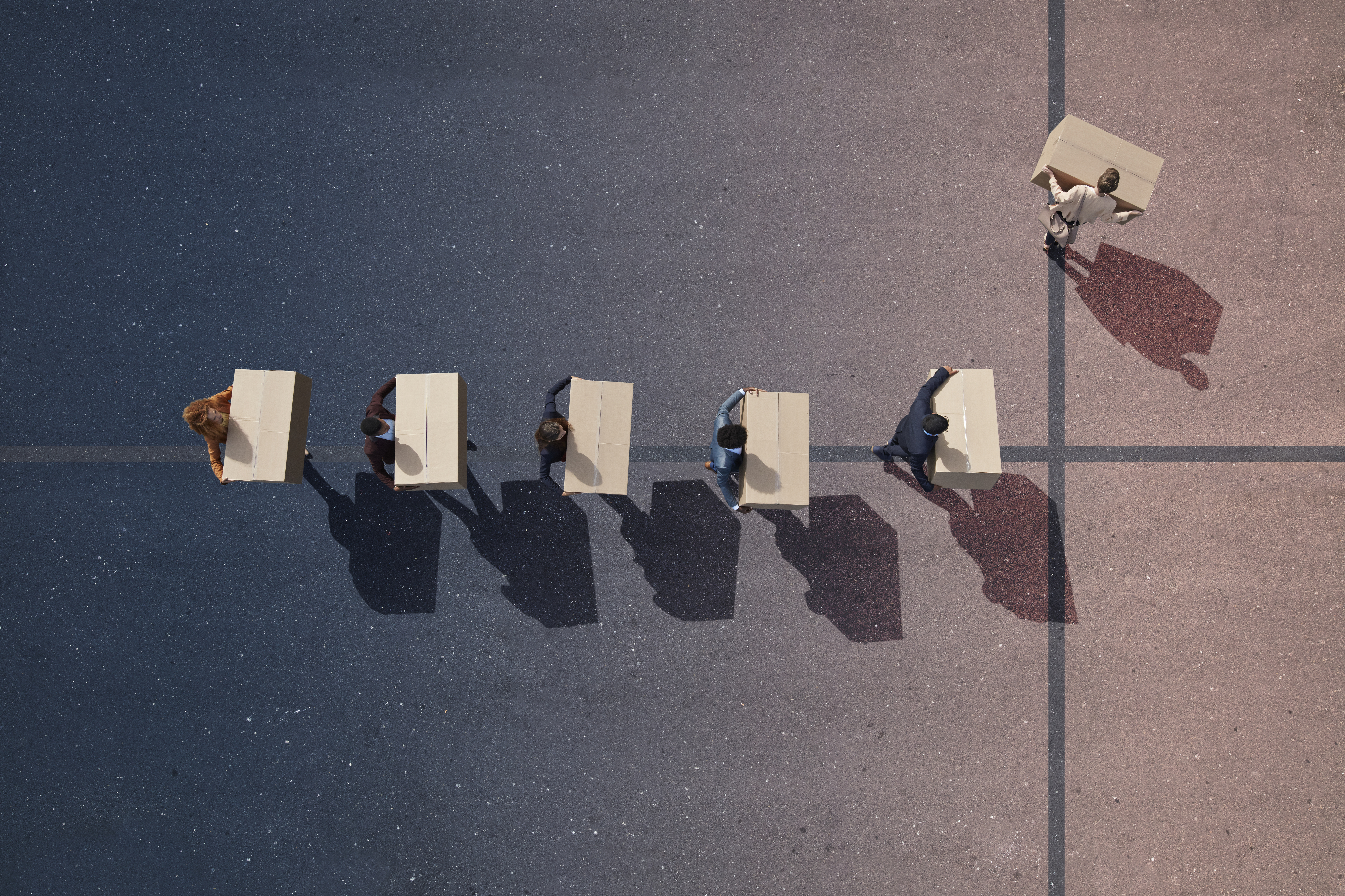 Line of employees in suits carrying boxes