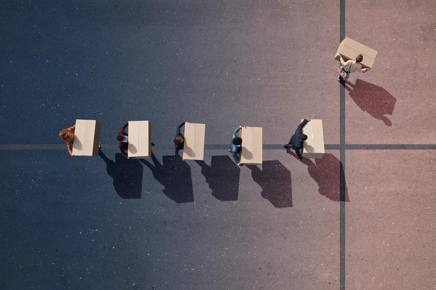 Line of employees in suits carrying boxes