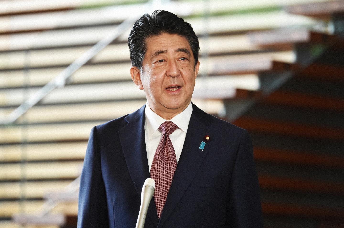 Shinzo Abe standing in front of a microphone speaking to the media.