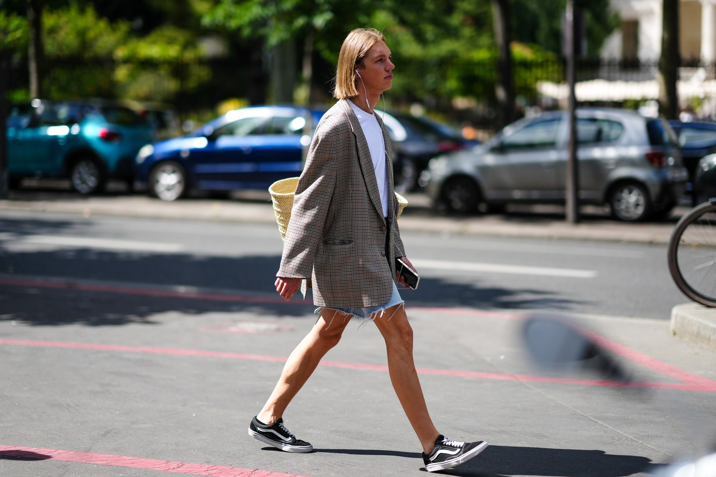 A person wearing a white t-shirt under a beige blazer with denim jorts.