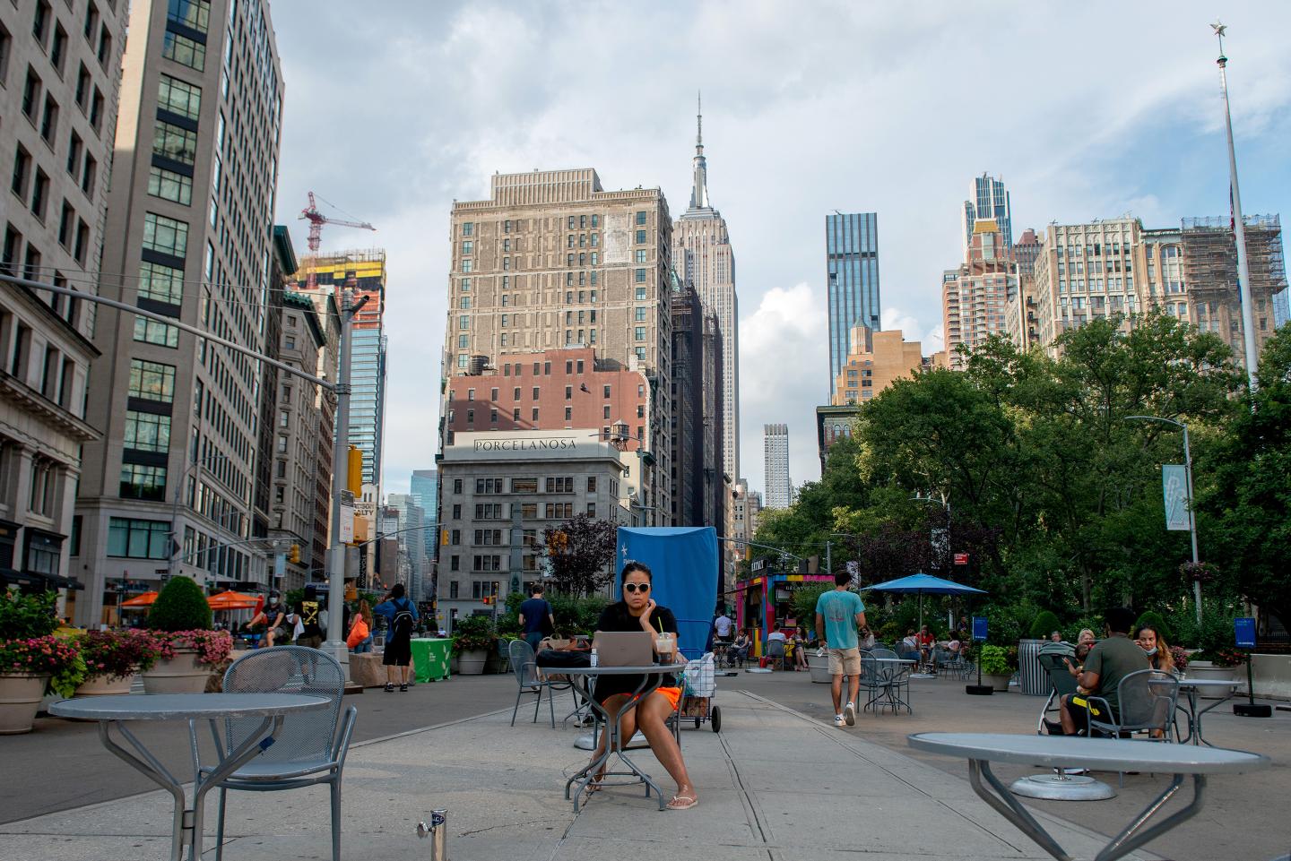 A woman works on her laptop at an outdoor table in Flatiron with a view of the Empire State Building.