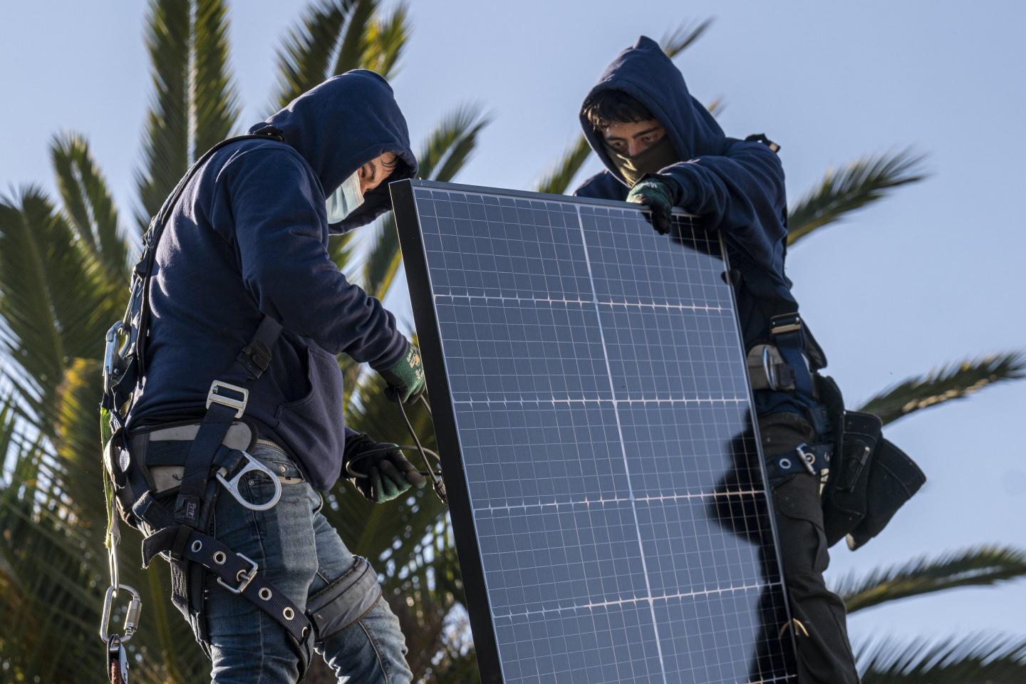 Contractors install solar panels.