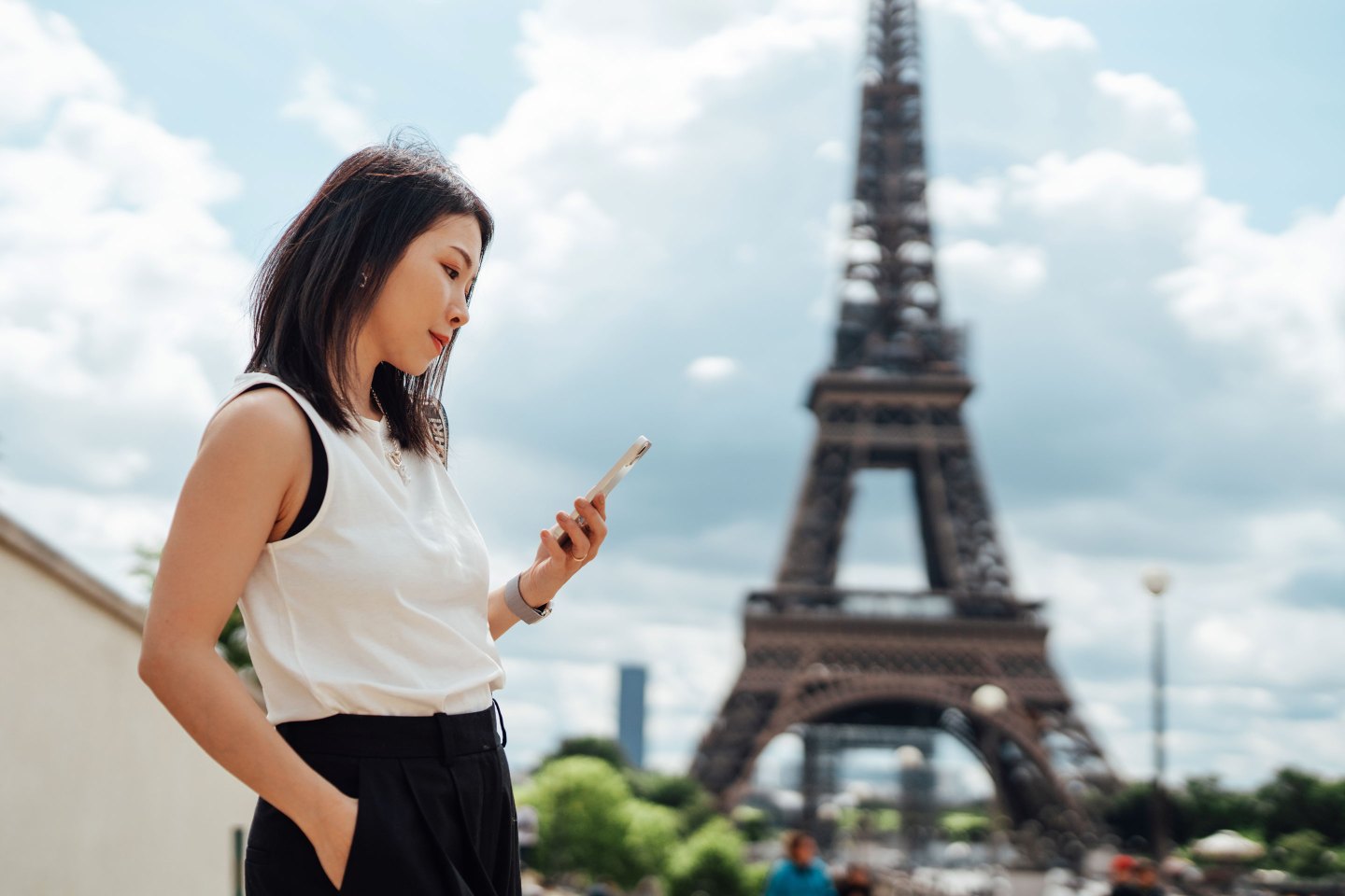 Businesswoman using smart phone while visiting Eiffel Tower in Paris on a work trip