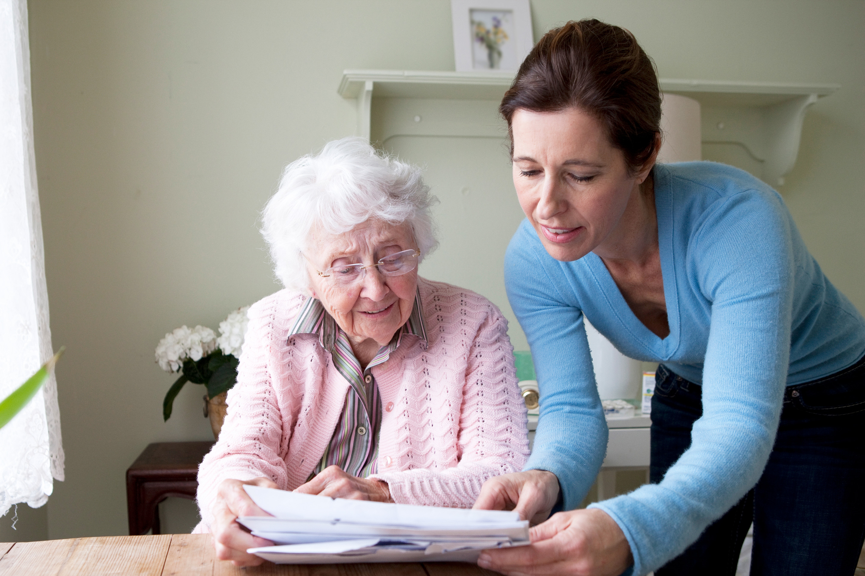 Woman reading to mother at table