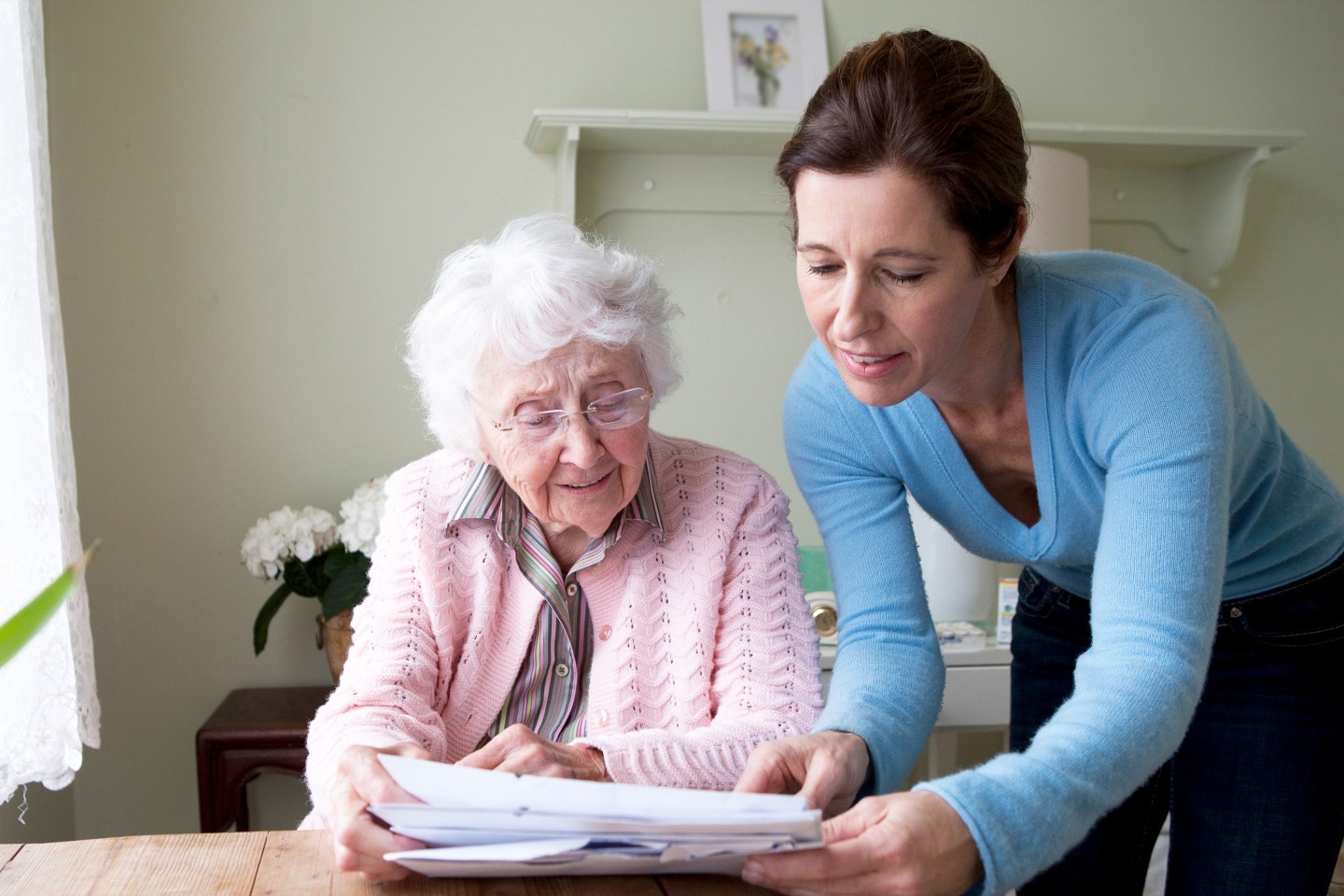 Woman reading to mother at table