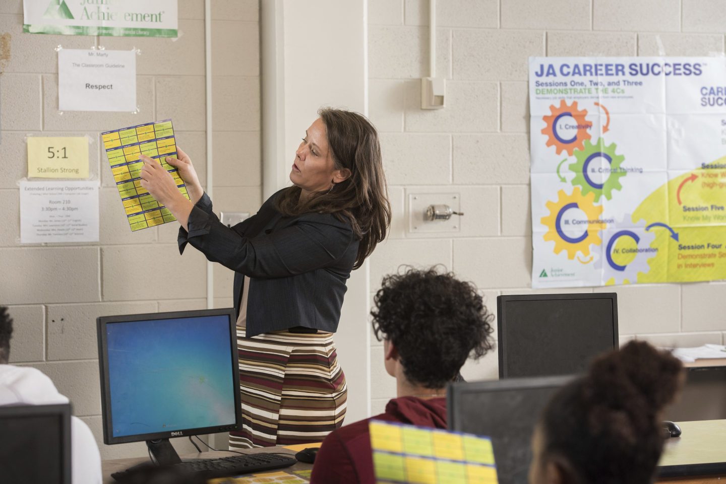 In this photo provided by Junior Achievement USA, volunteer Cammy Elquist LoRé teaches a Colorado Springs, Colo., high school class program that helps prepare them for handling finances in the adult world, on March 23, 2018.