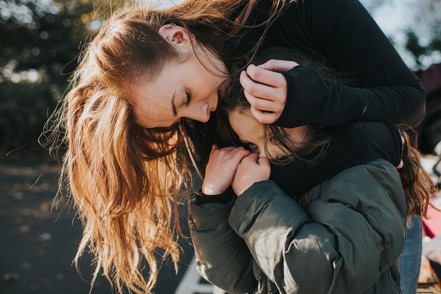Young girl grips her mother’s arm tightly