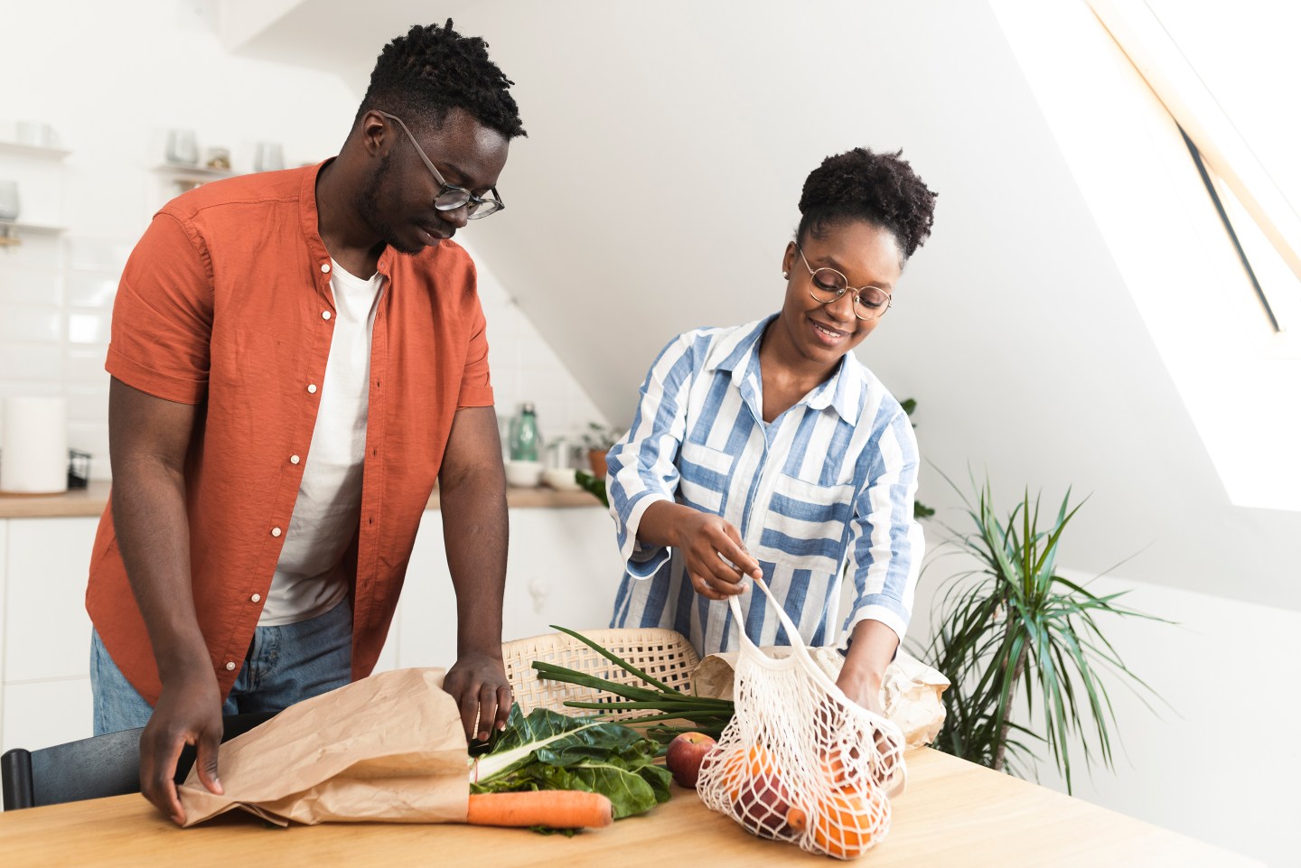 Young African American couple coming back from the supermarket and unpacking shopping bags.