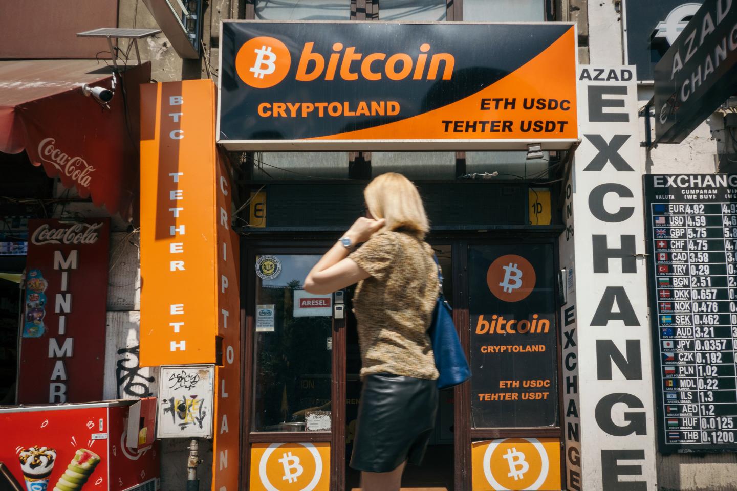 A woman walks past a Bitcoin crypto ATM next door to a currency exchange office.