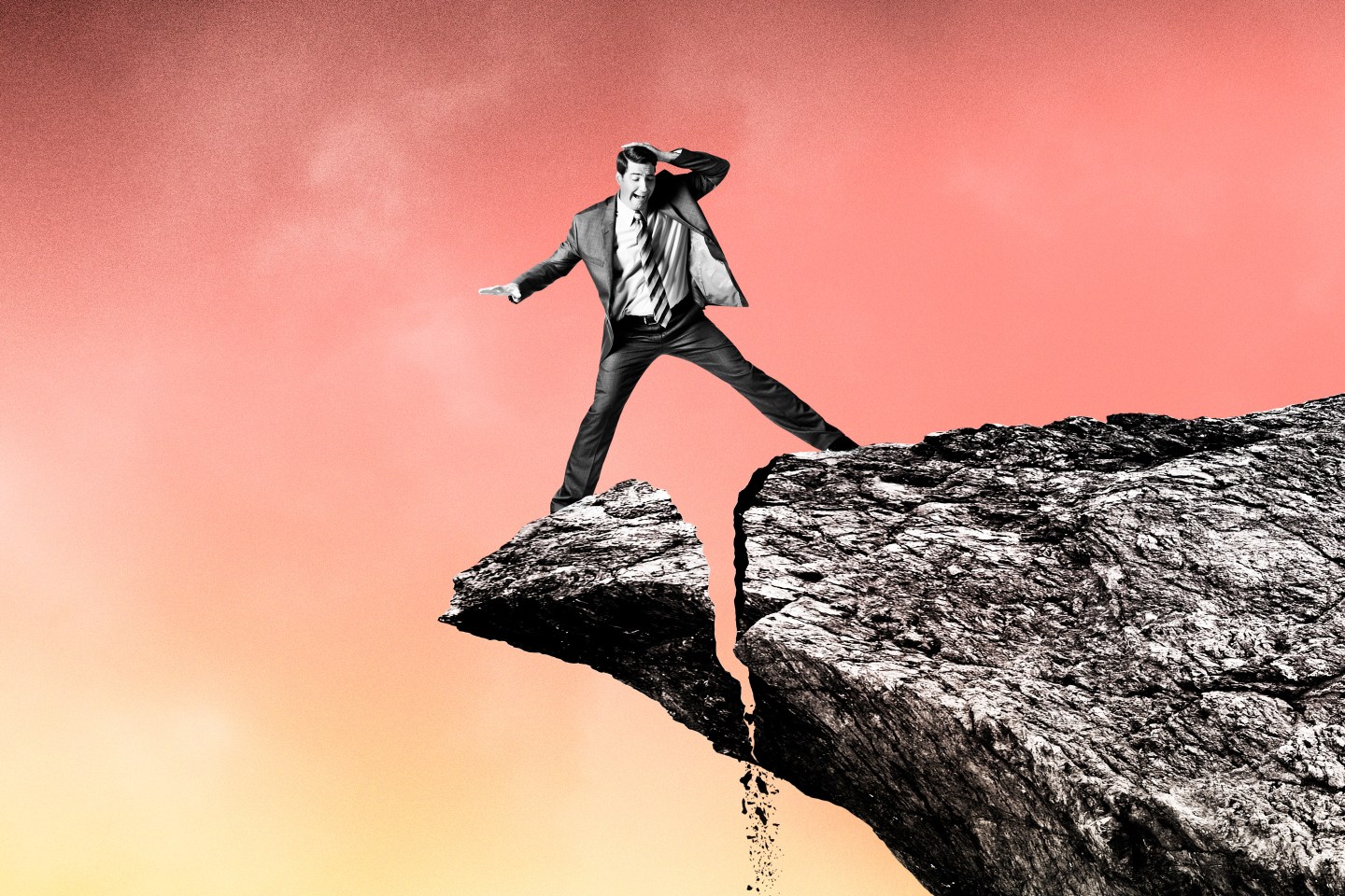 A man straddles a broken cliff.