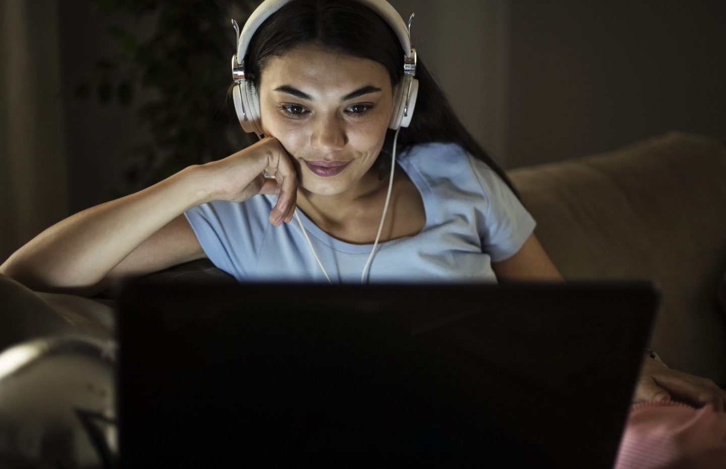 Single woman watching online tv in the night sitting on a couch in the living room at home
