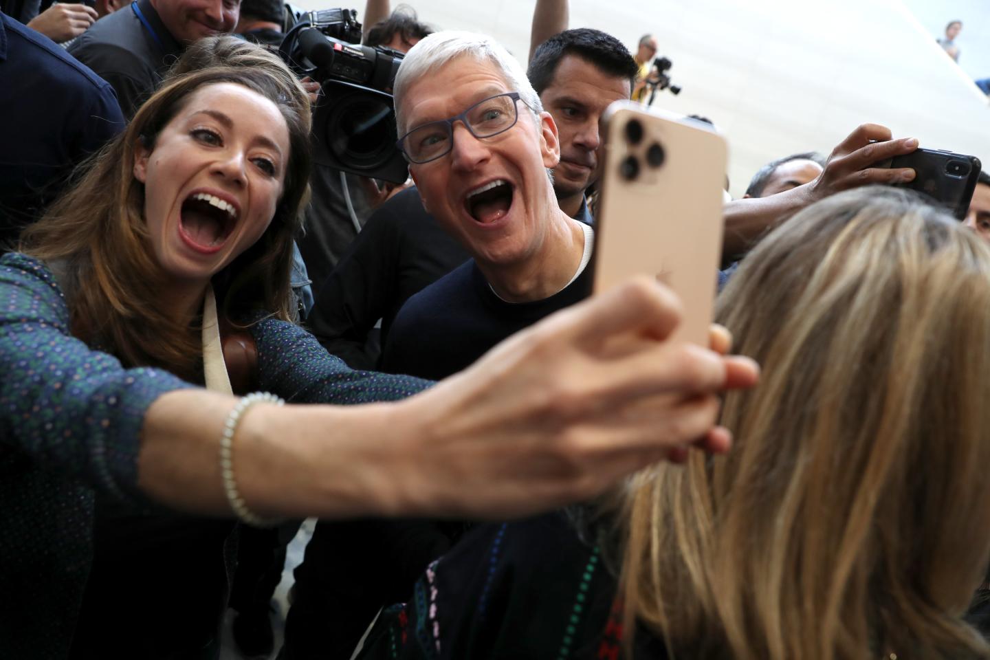Apple CEO Tim Cook and a woman take a selfie together.