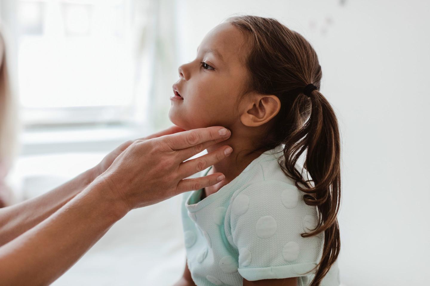 Cropped hands of doctor examining girl's throat in hospital