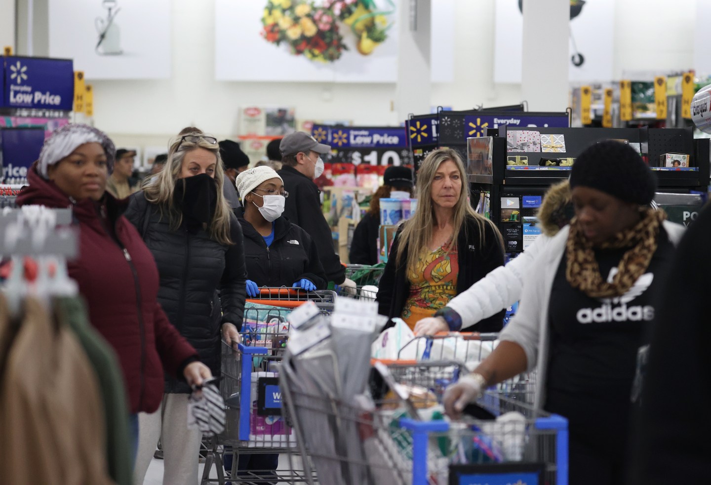 People wearing masks and gloves wait to checkout at Walmart.