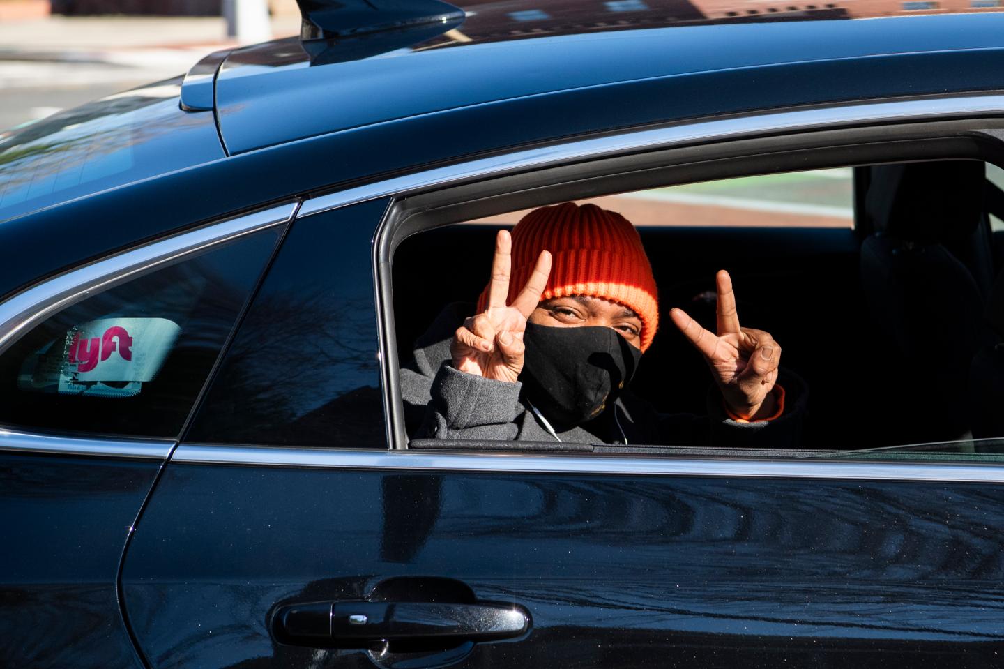 A rider in a Lyft car gives the peace sign