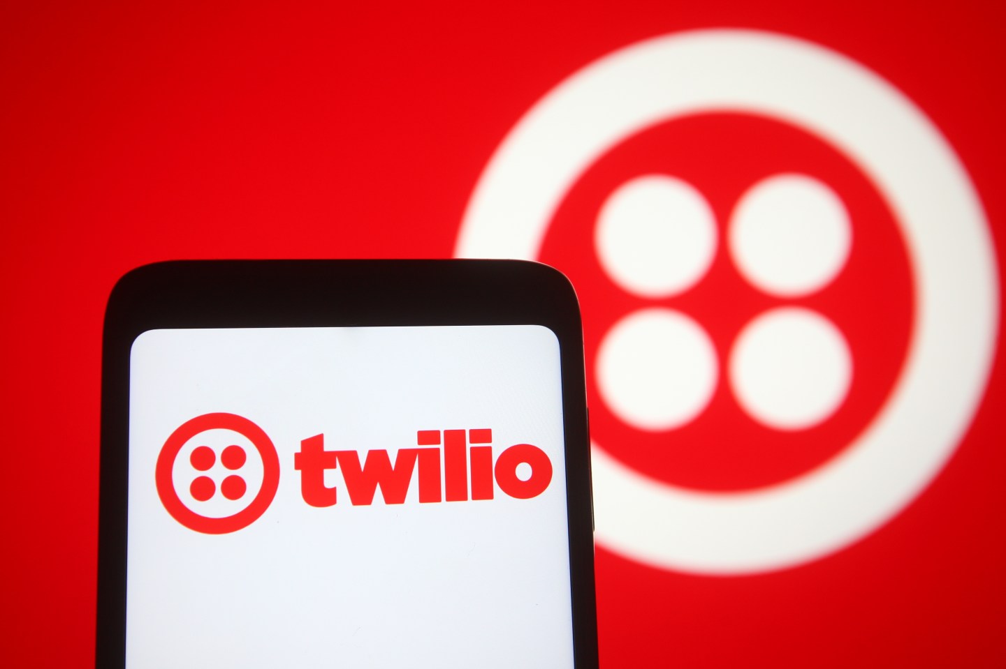 In this photo illustration a Twilio logo of an US cloud communications platform is seen on a smartphone and a pc screen.
