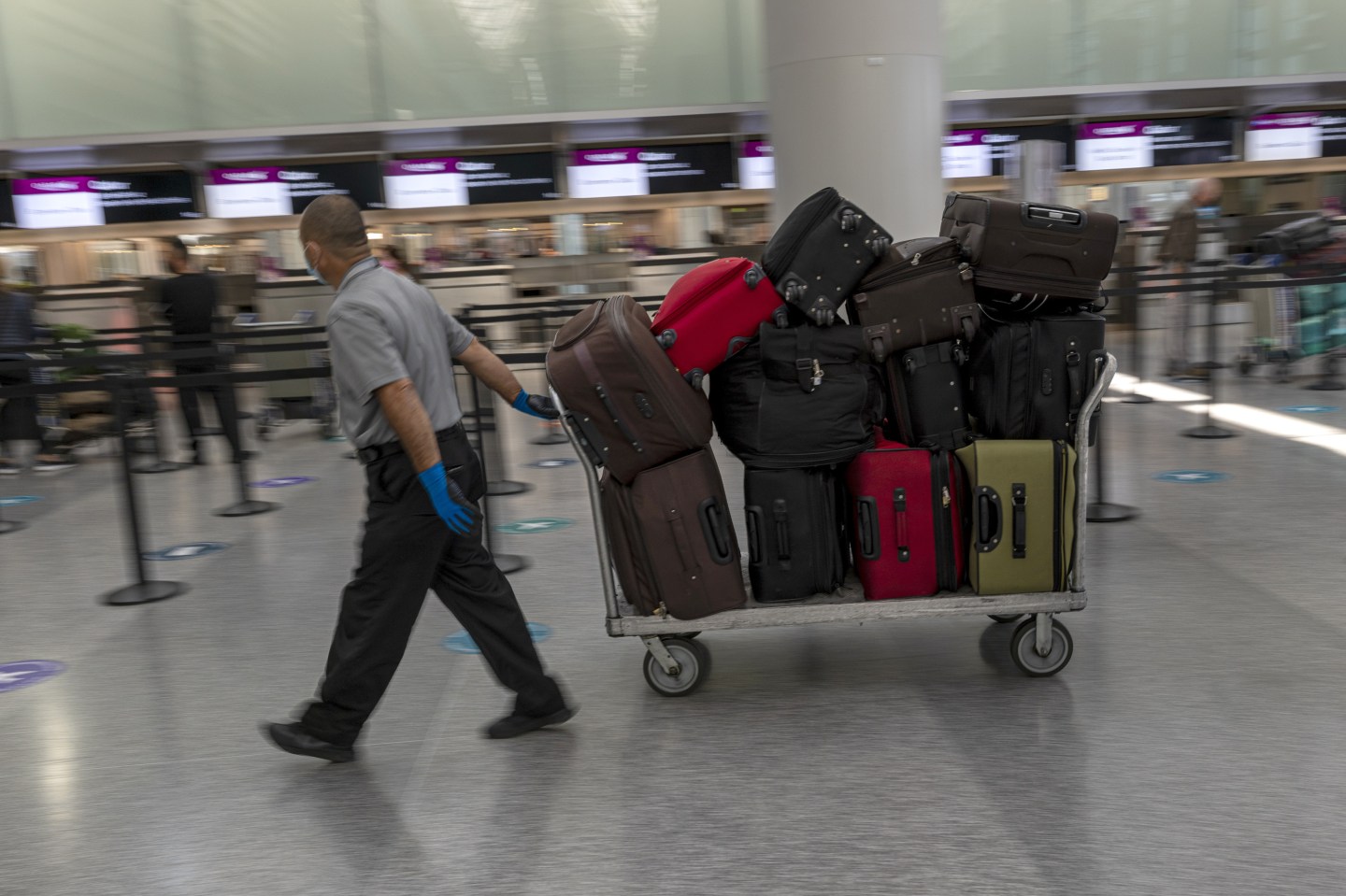Baggage handler carrying a tray full of luggage in San Francisco's airport