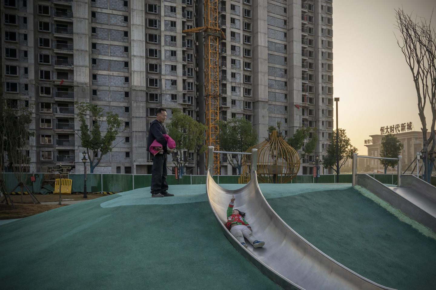 A child on a slide in front of unfinished apartment buildings in Wuhan, China.