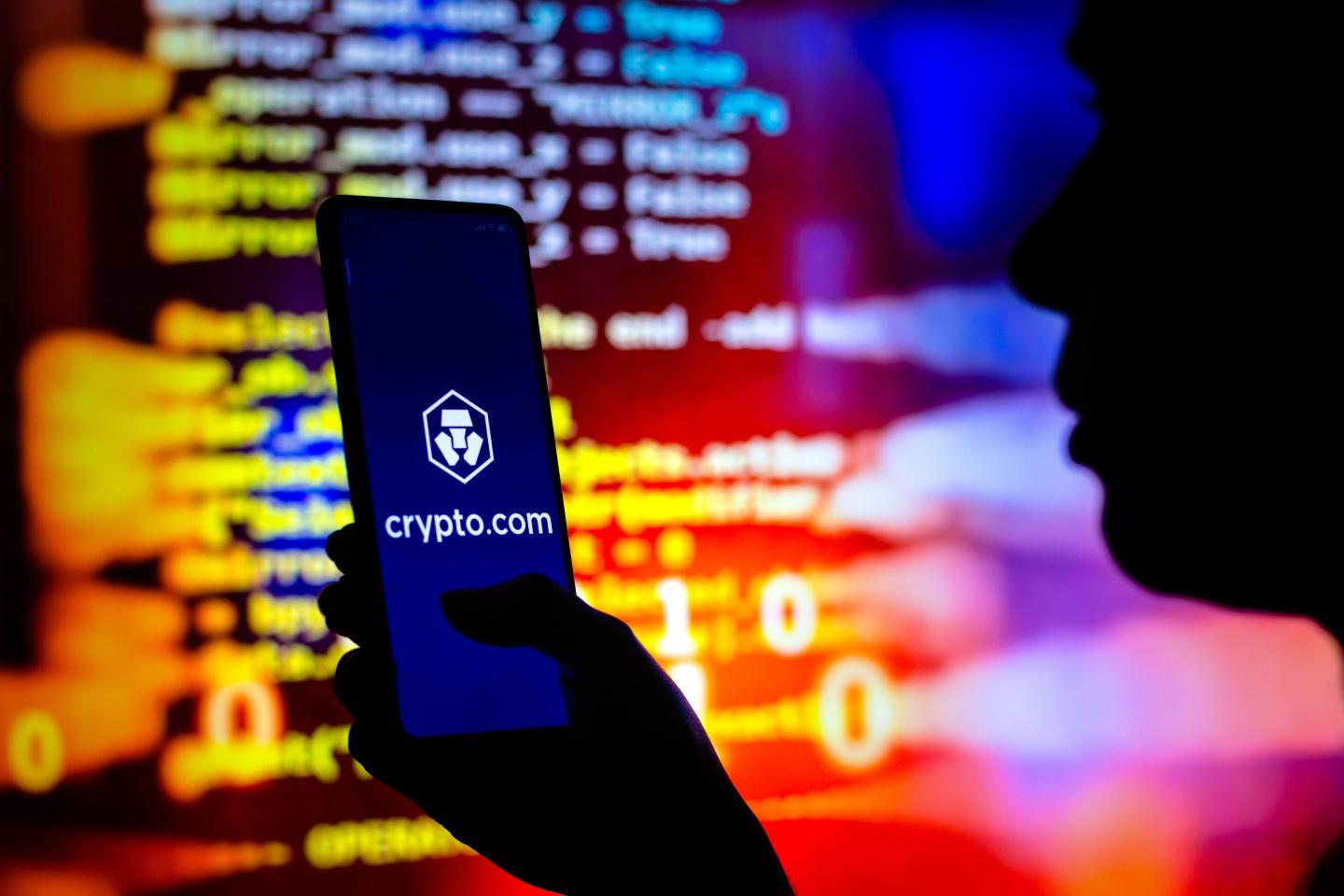 a woman holds a smartphone with the Crypto.com logo