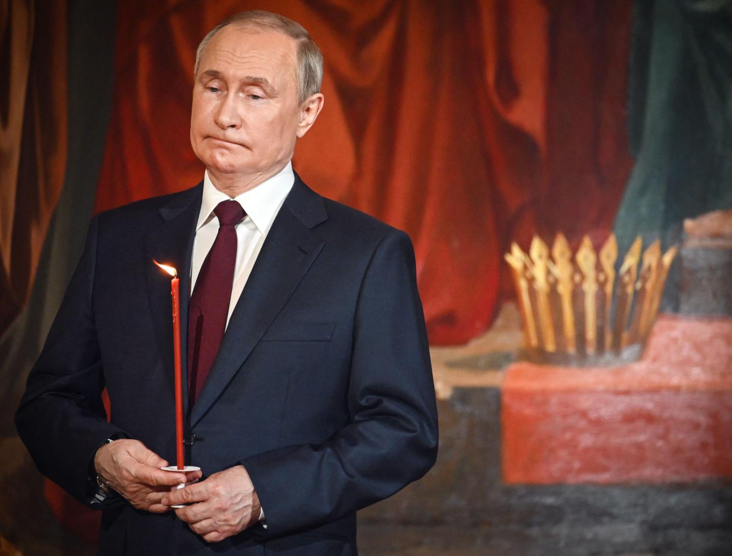 Photo of Russian President Vladimir Putin holding a candle during Orthodox Easter service on April 23, 2022, in Moscow, Russia.