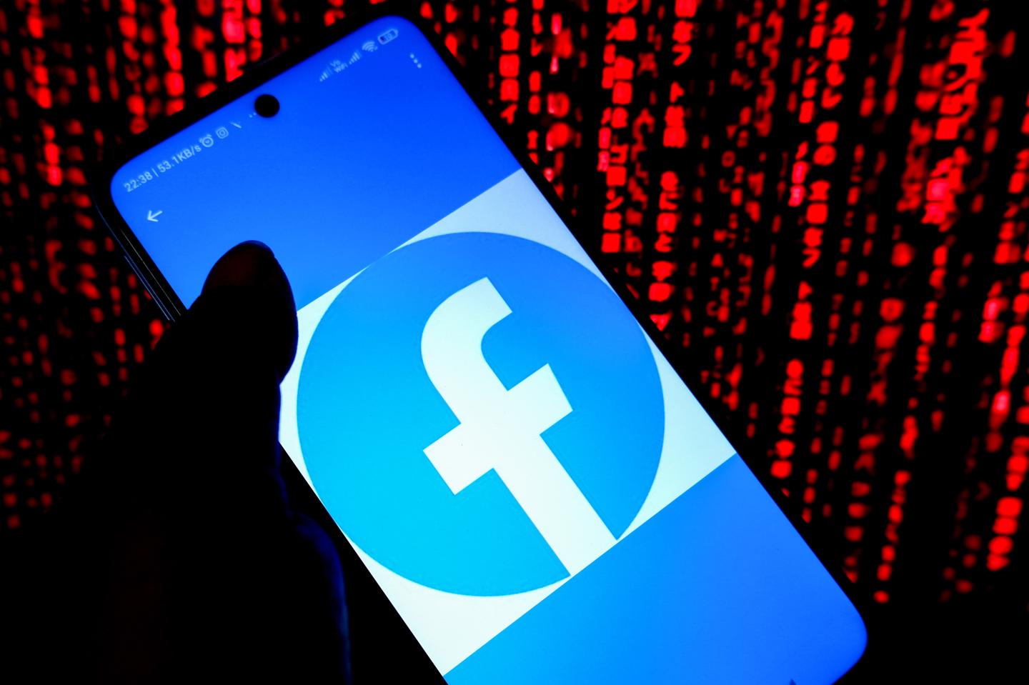 A Facebook logo is displayed on a smartphone screen surrounded by lines of red code