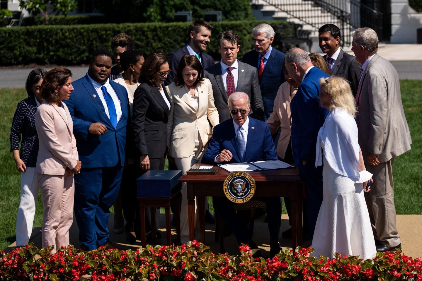 President Joe Biden signs the Chips and Science Act while surrounded by guests