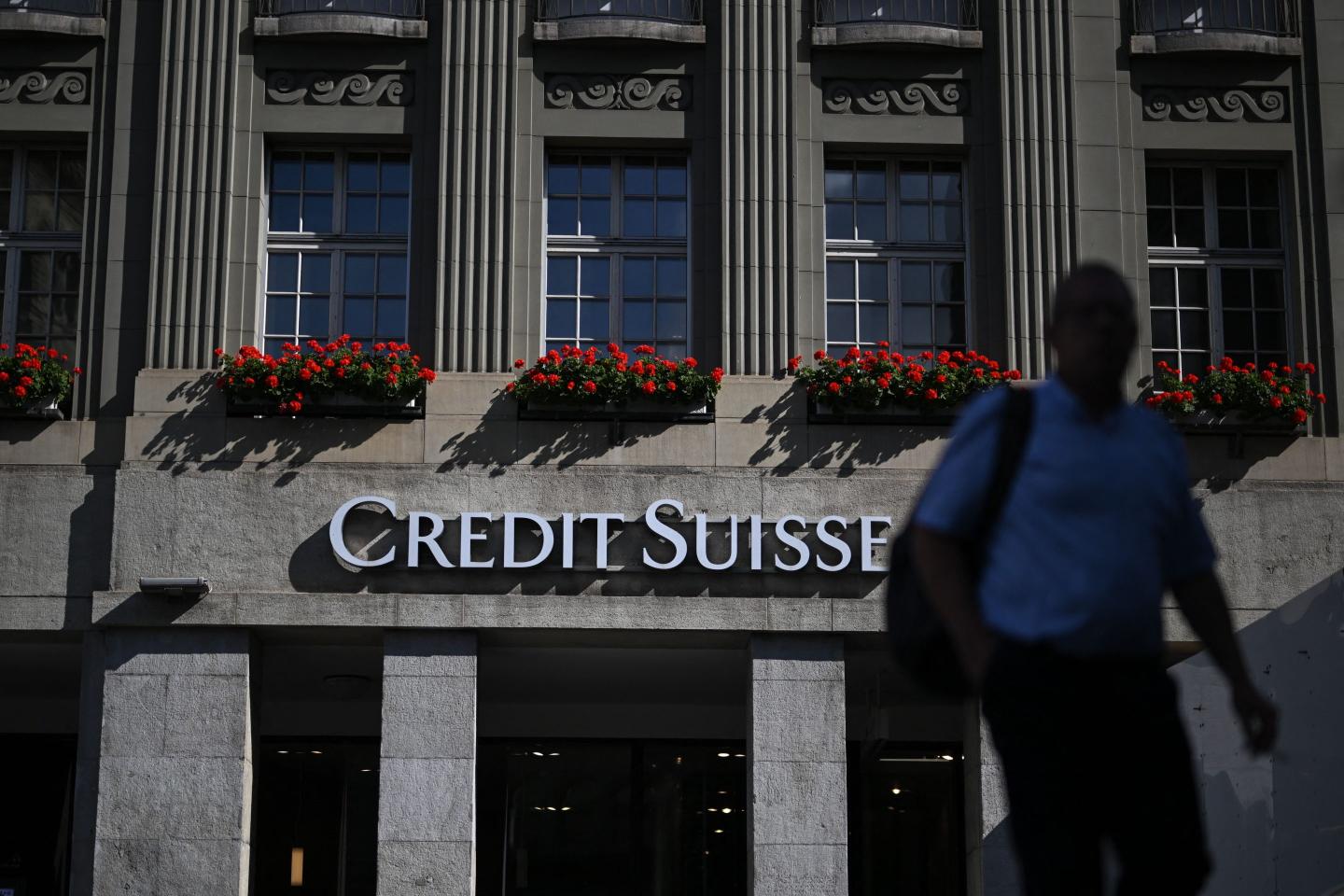 A man walks next to a branch of Swiss banking giant Credit Suisse