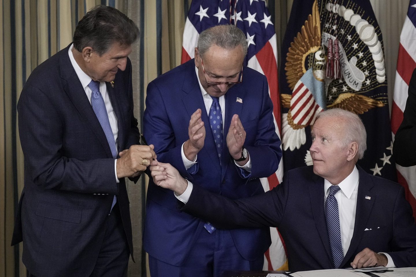 President Joe Biden (right) gives Sen. Joe Manchin (D-W.Va.) (left) the pen he used to sign the Inflation Reduction Act with Senate Majority Leader Charles Schumer (D-N.Y.) at the White House on Aug. 16, 2022.
