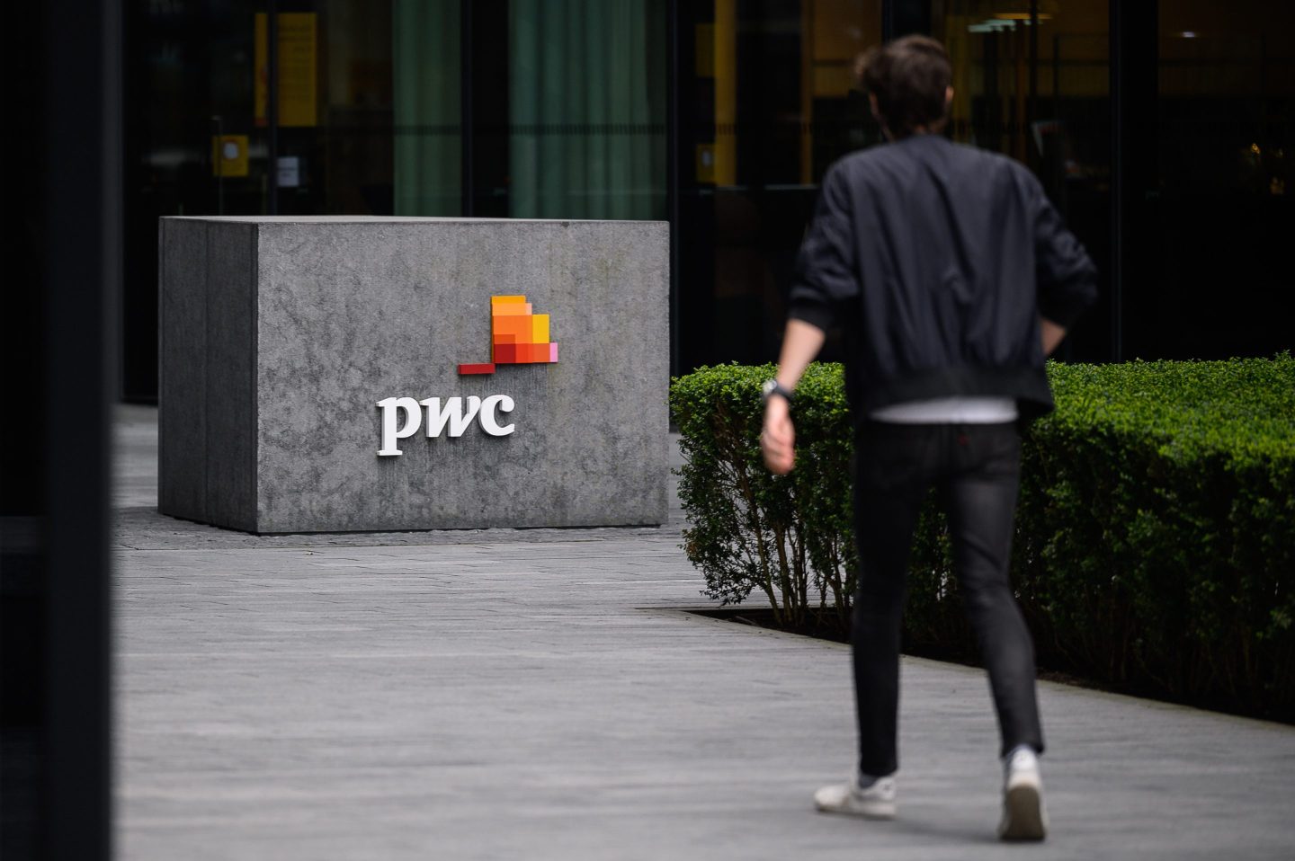 A man is seen walking past the PwC offices in London, England.
