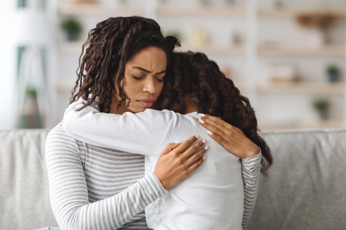 Closeup of mom hugging her upset daughter.