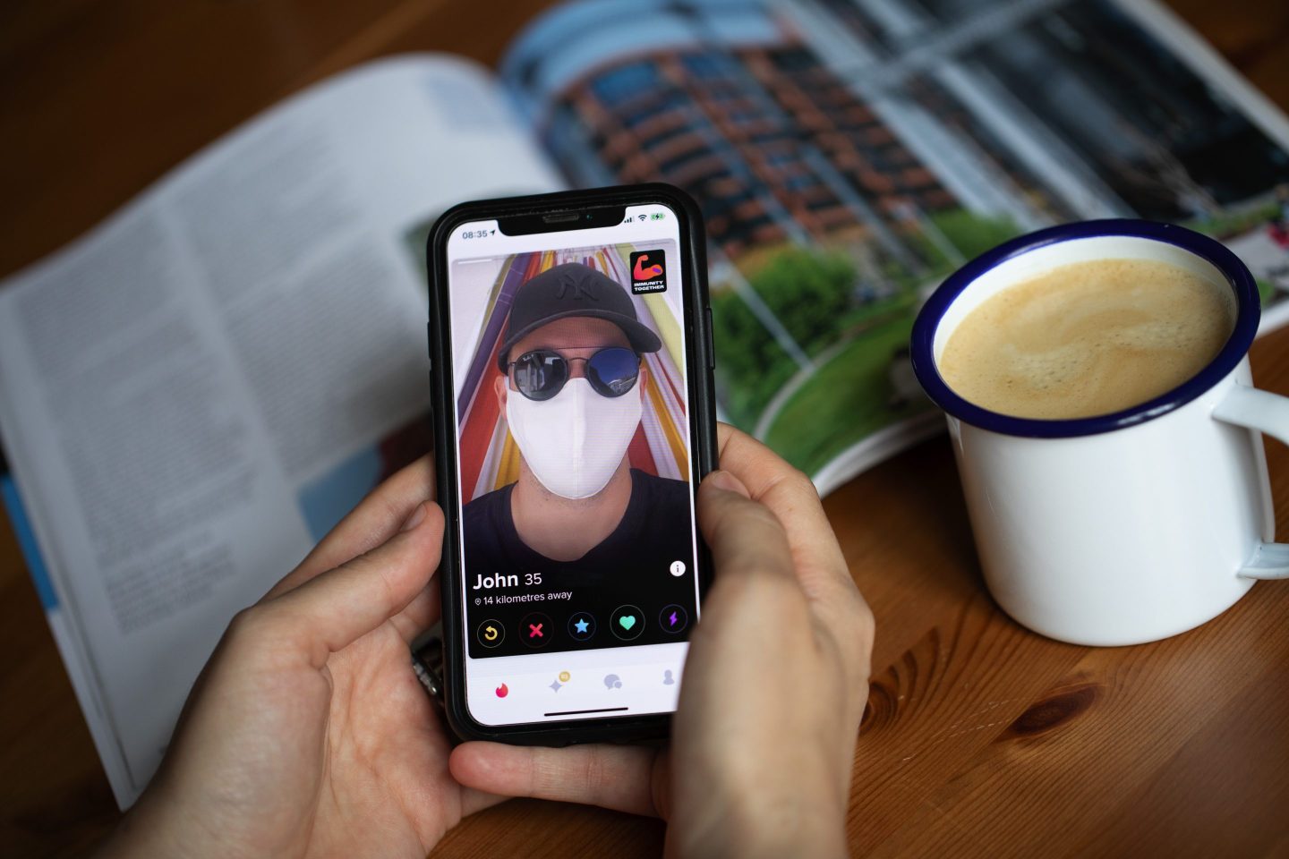 A person holds a phone featuring a Tinder profile.