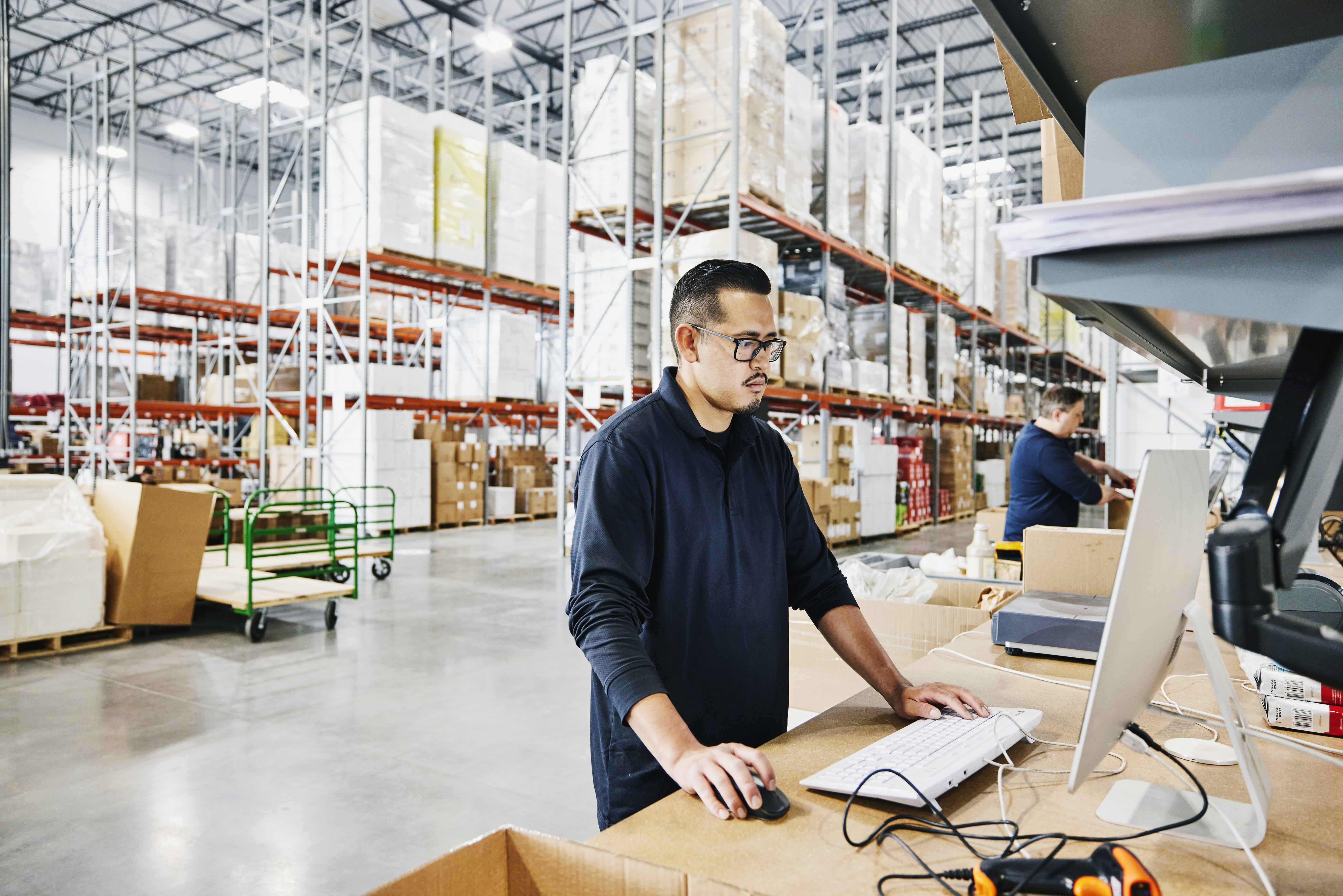 A man looking at a computer in a warehouse.