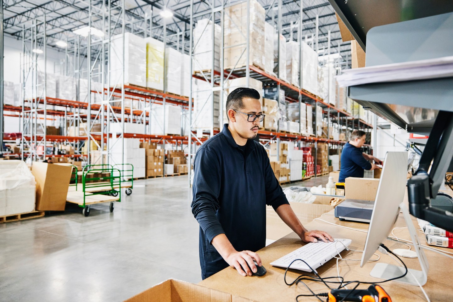 A man looking at a computer in a warehouse.