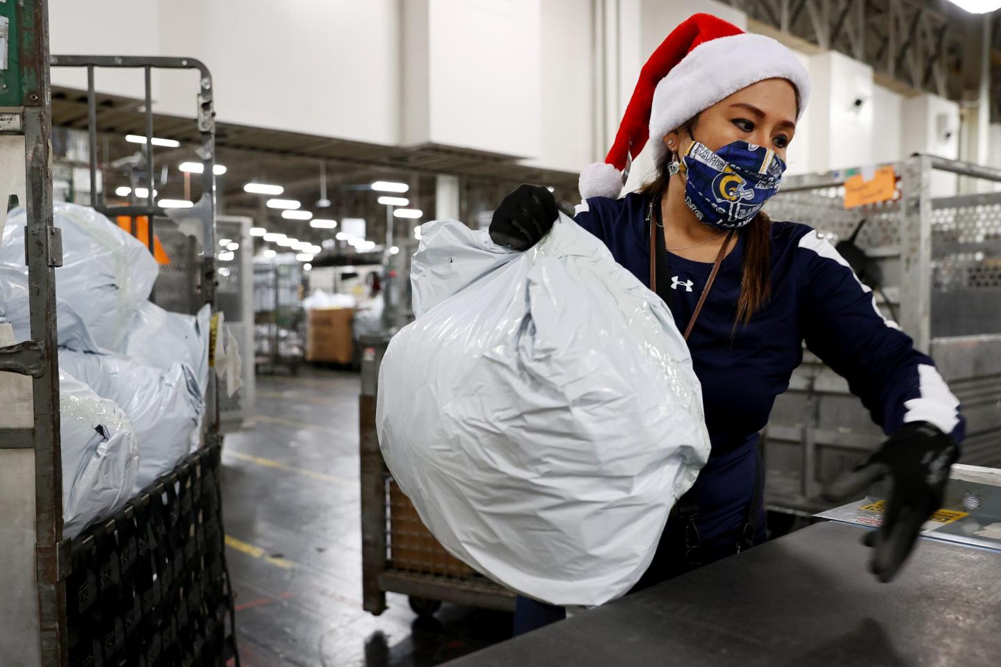 A US postal service employee wearing a Santa hat.
