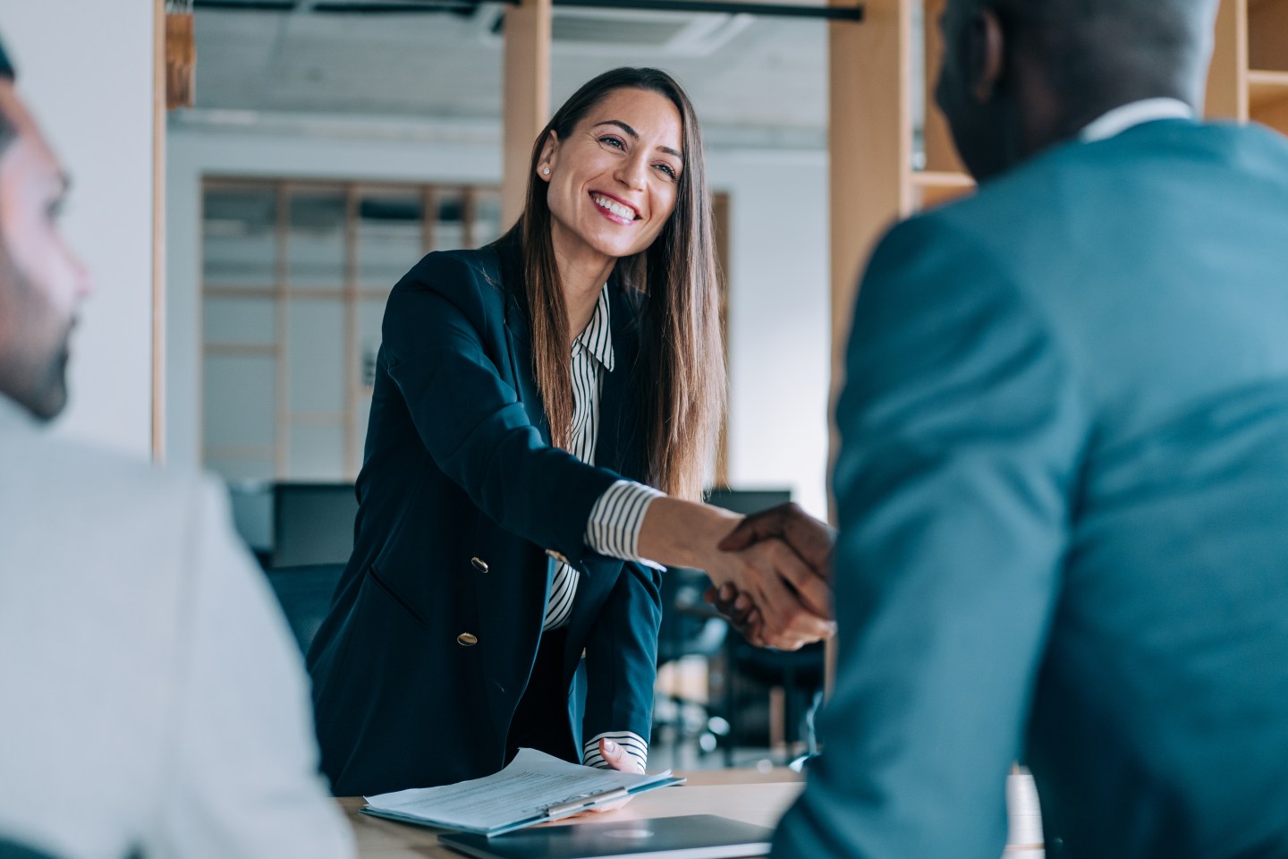 Business woman shakes hands with business man over table