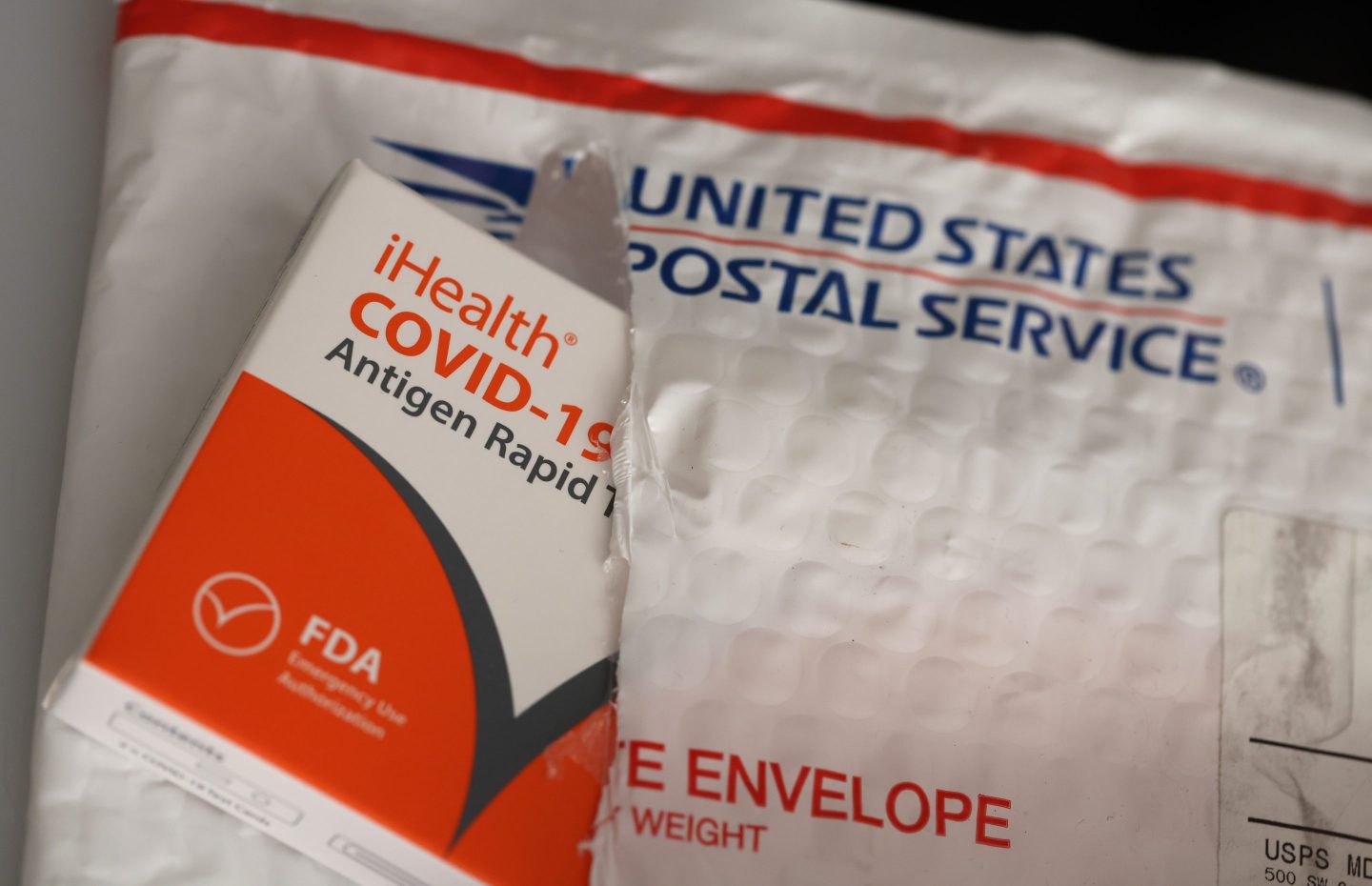In this photo illustration, free iHealth COVID-19 antigen rapid tests from the federal government sit on a U.S. Postal Service envelope after being delivered on Feb. 4 in San Anselmo, Calif.